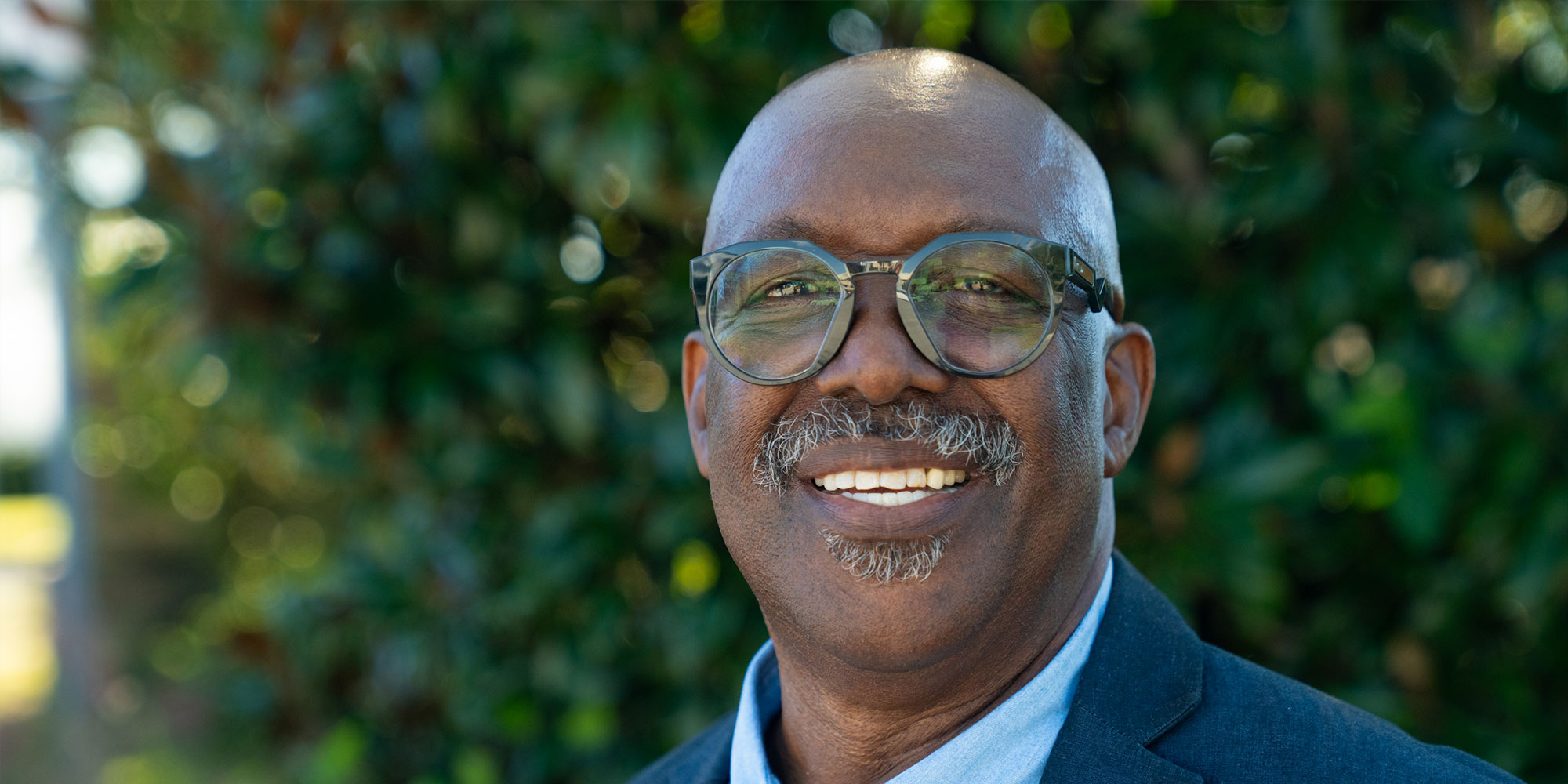 headshot of patient smiling brightly outside of the dental center