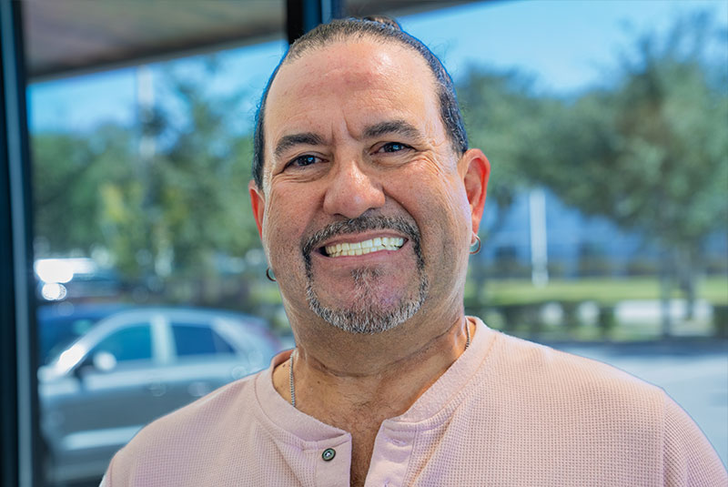 Headshot of Patient smiling brightly outside of the dental center